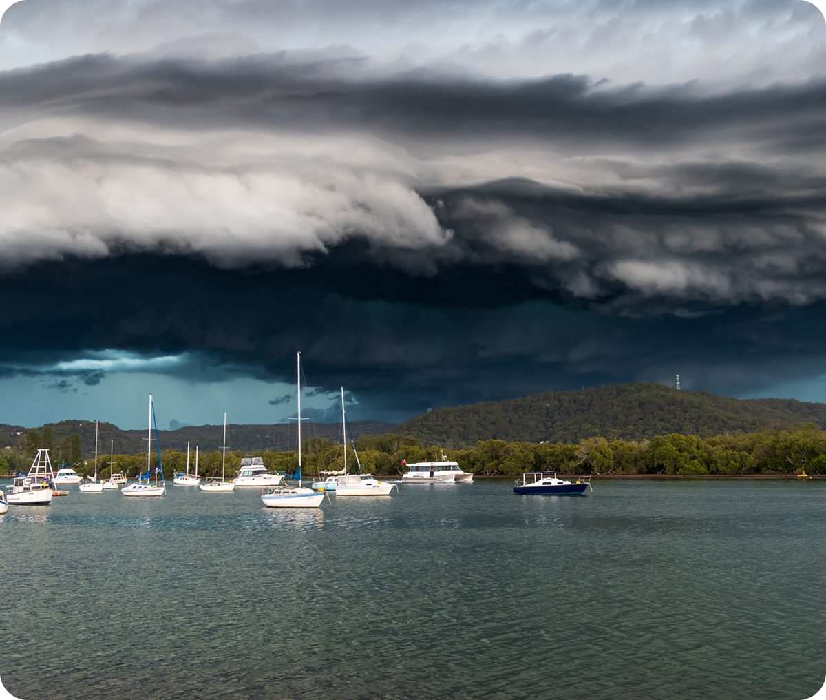 Storm clouds over boats on calm water.